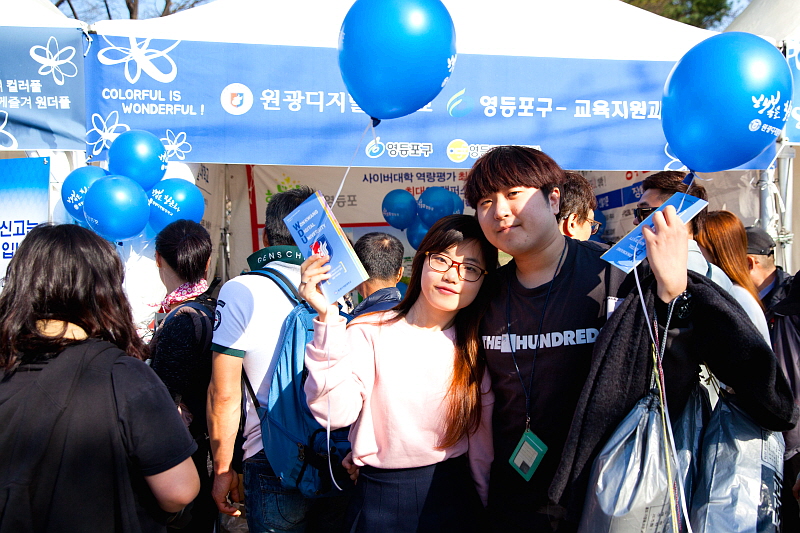 원디대 부스 앞에서 학교 리플렛과 풍선을 들고 있는 시민들